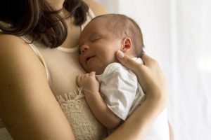 Mother holds her baby to her chest in a loving embrace.