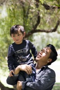 Father holds his young son on his shoulders at an outdoor park.