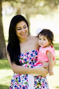 Mother holds her daughter outdoors for a family photoshoot